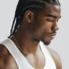 Man looking down to the right wearing about 12 cornrows that reach his shoulders